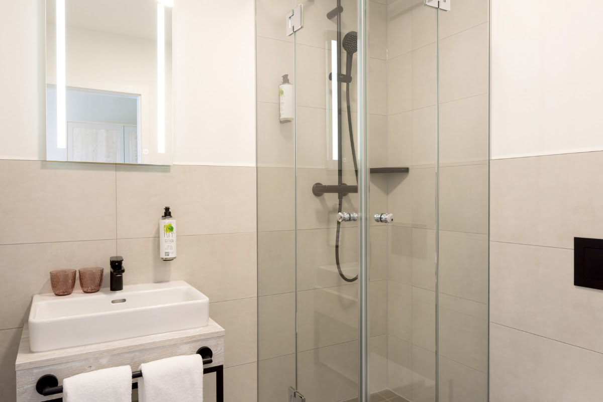 Modernes Badezimmer mit Dusche, Waschbecken und eleganter Ausstattung im Doppelzimmer des Koopmanns Hotel.