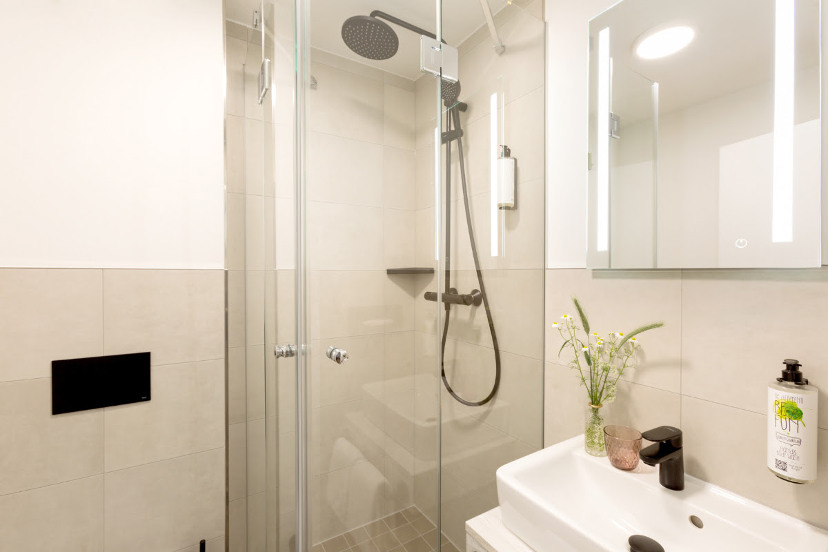 Modern eingerichtetes Bad mit großer Dusche, beleuchtetem Spiegel und Waschbereich im Doppelzimmer des Koopmanns Hotels.