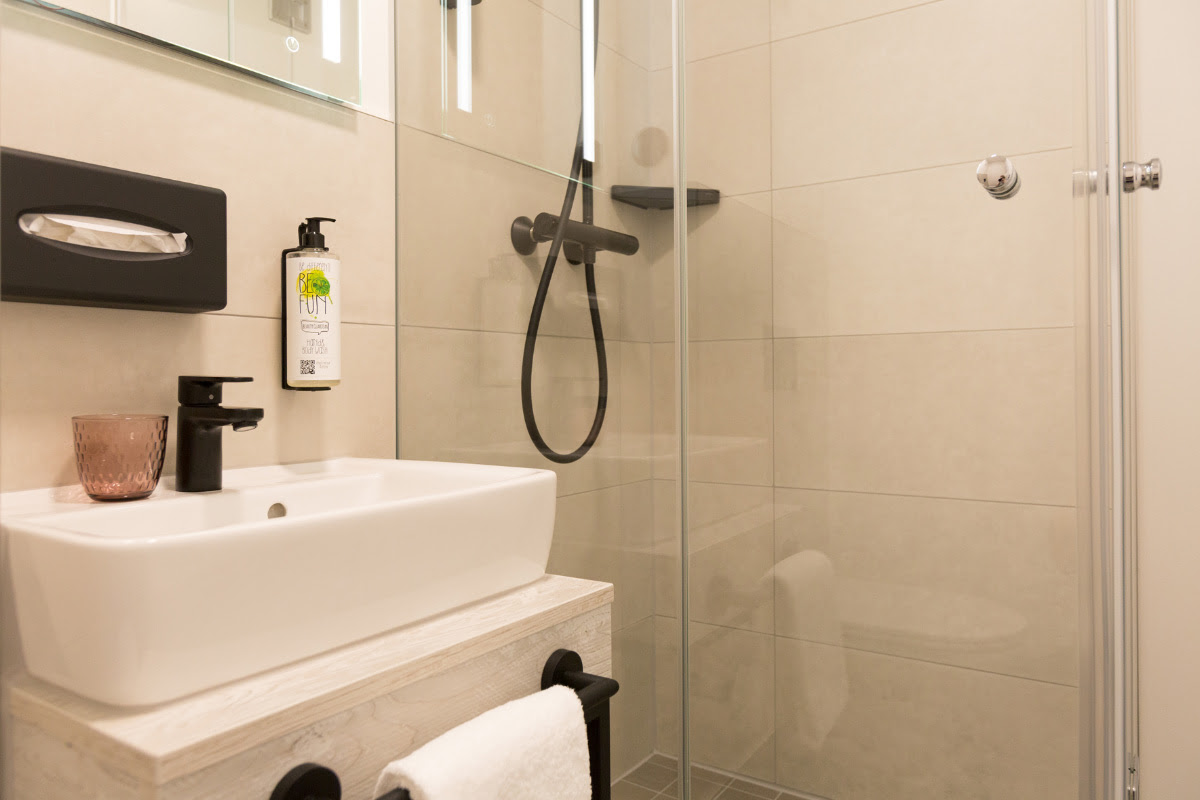 Bright bathroom with shower, washbasin and modern furnishings in the single room of the Koopmanns Hotel.