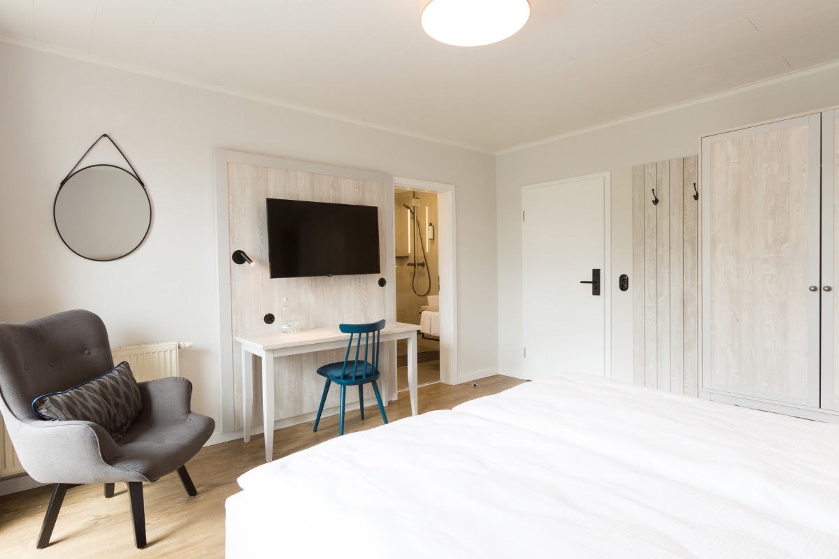 Komfort-Doppelzimmer mit modernem Design, ausgestattet mit TV, Schreibtisch und gemütlichem Sessel im Koopsmanns Hotel.