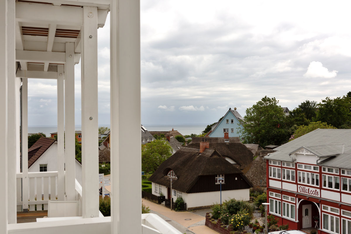 Blick vom Balkon eines Einzelzimmers im Koopmanns Hotel auf Reetdächer, traditionelle Häuser in Göhren und die Ostsee.