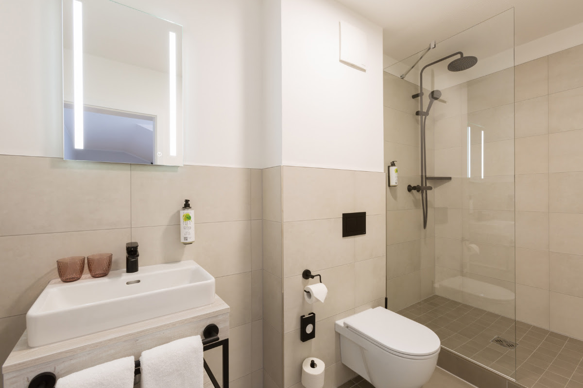 Modernes Bad mit klaren Linien und Regendusche im Superior-Doppelzimmer des Koopmanns Hotel &amp; Lädchen in Göhren.