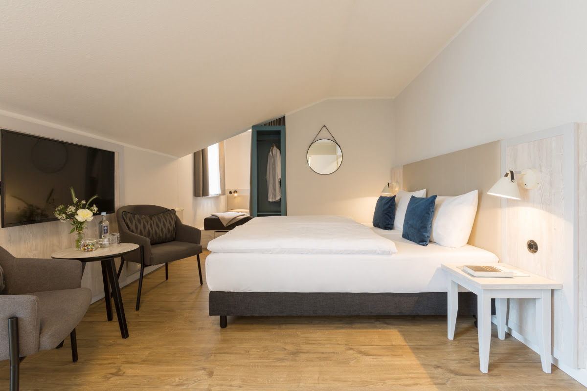 Geräumiges Superior-Doppelzimmer mit Doppelbett, gemütlichem Sitzbereich und moderner Ausstattung im Koopmanns Hotel.