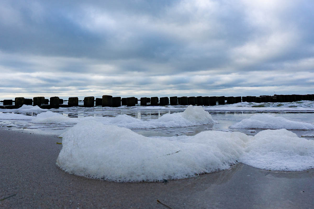 Whitecaps of the Baltic Sea roll onto the beach with dramatic skies over the sea during your vacation at the Hotel Seezeichen.