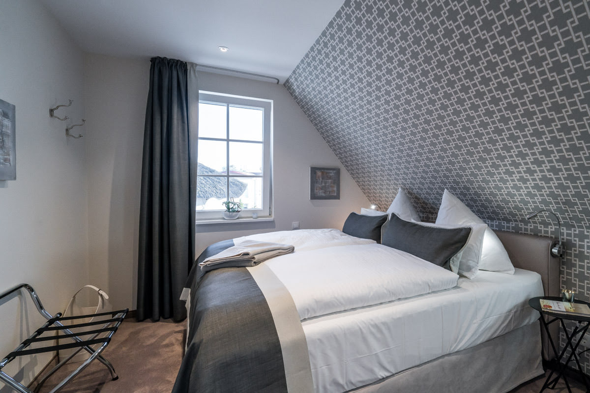 Doppelbett im Ferienhaus Seewind des Hotel Künstlerquartier Seezeichen mit stilvollem Design und gemütlichen Kissen.
