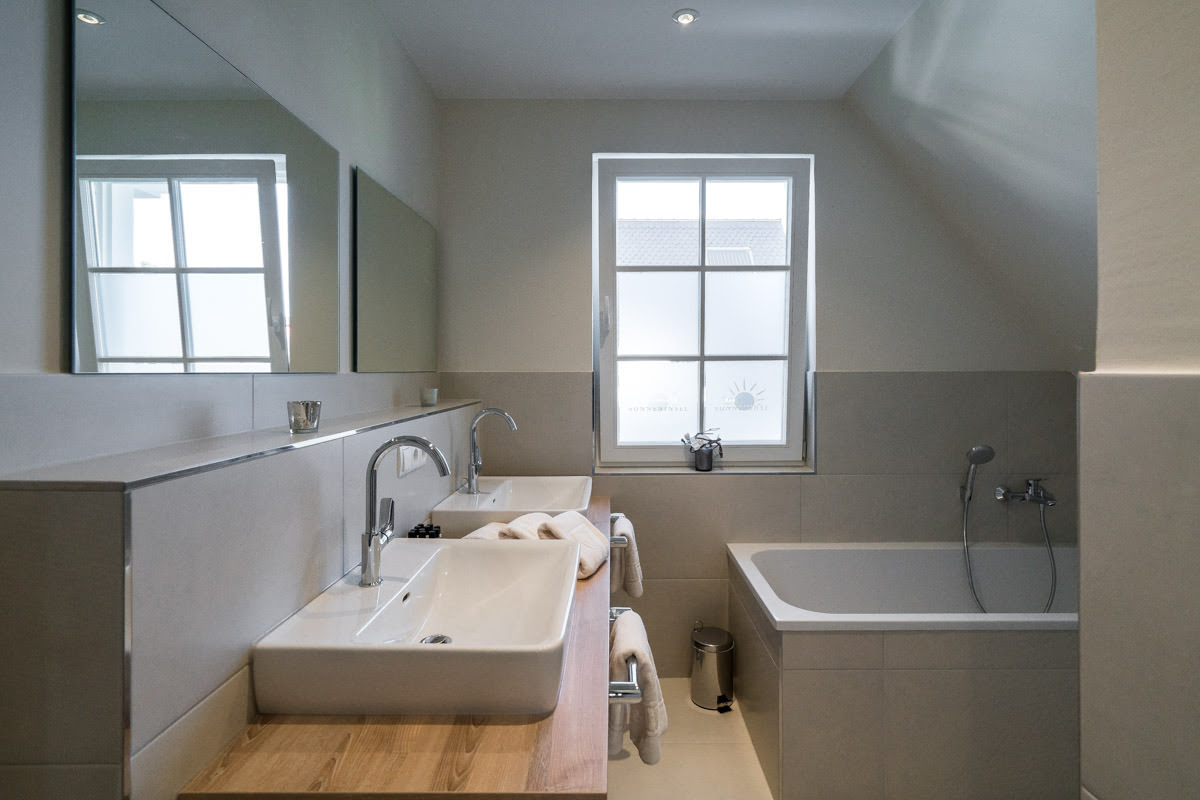 Light-flooded bathroom with bathtub, modern furnishings and comfort in the Sonneninsel vacation home at Hotel Seezeichen.
