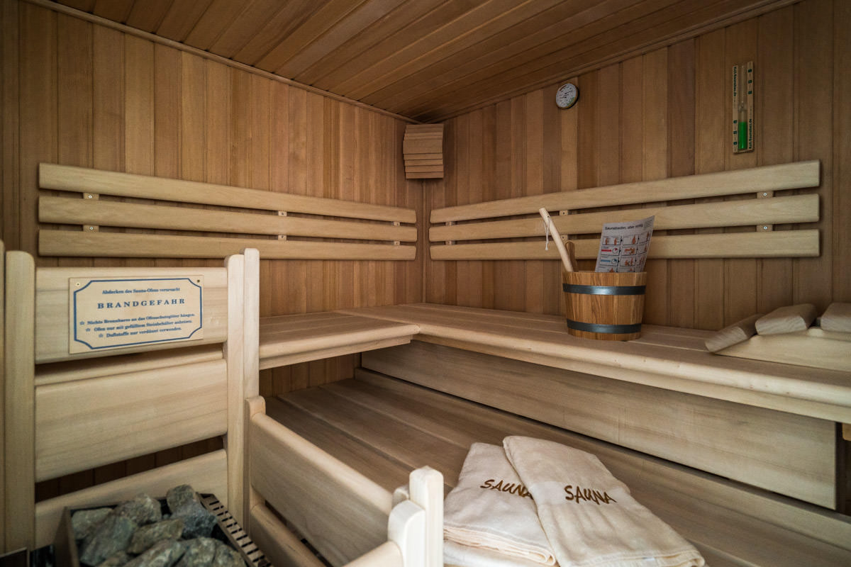 Private sauna made of light wood in the Sonneninsel vacation home with towels, part of the Hotel Künstlerquartier Seezeichen.