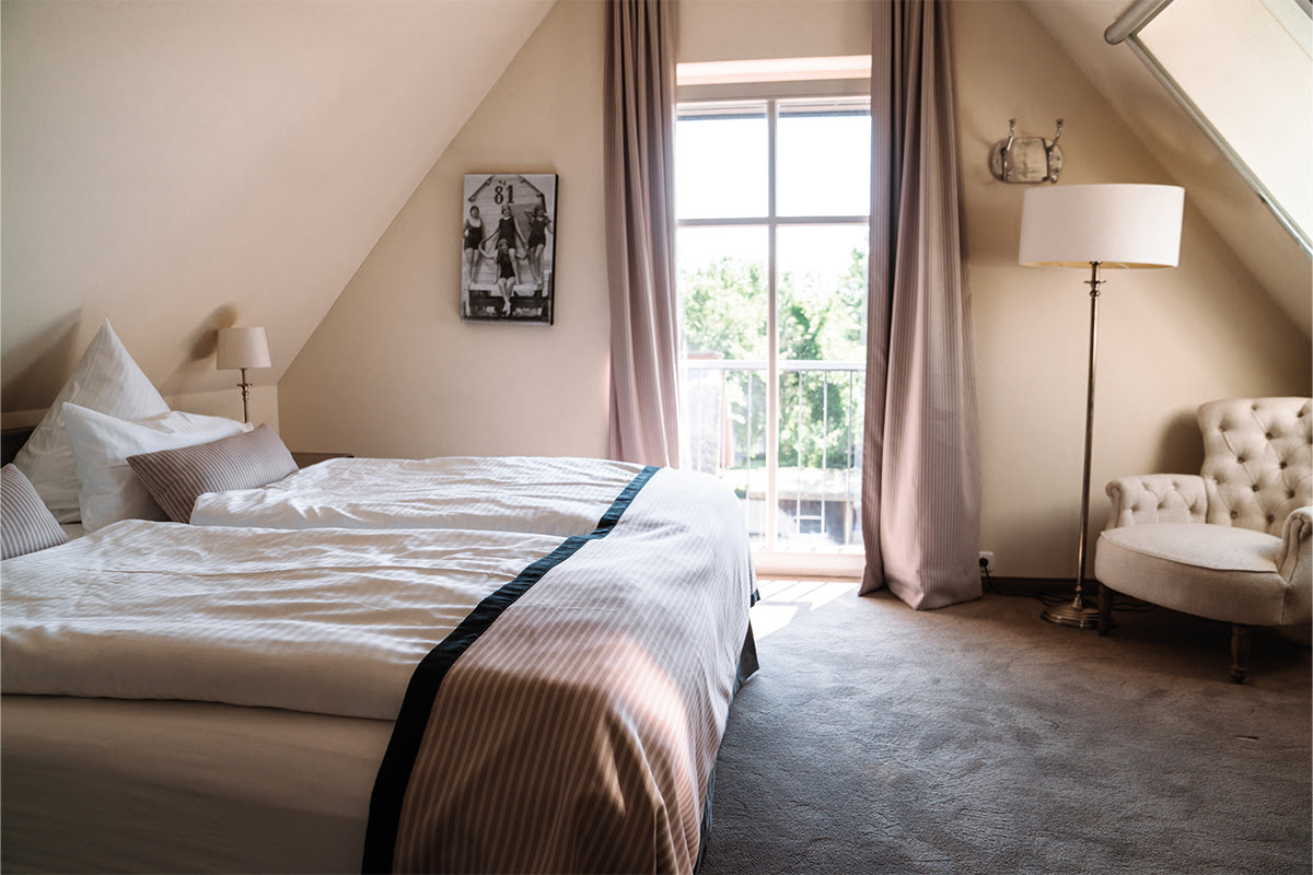 Cozy bedroom in the Dünenpark vacation apartment with large bed and sea view, part of the Hotel Künstlerquartier Seezeichen.