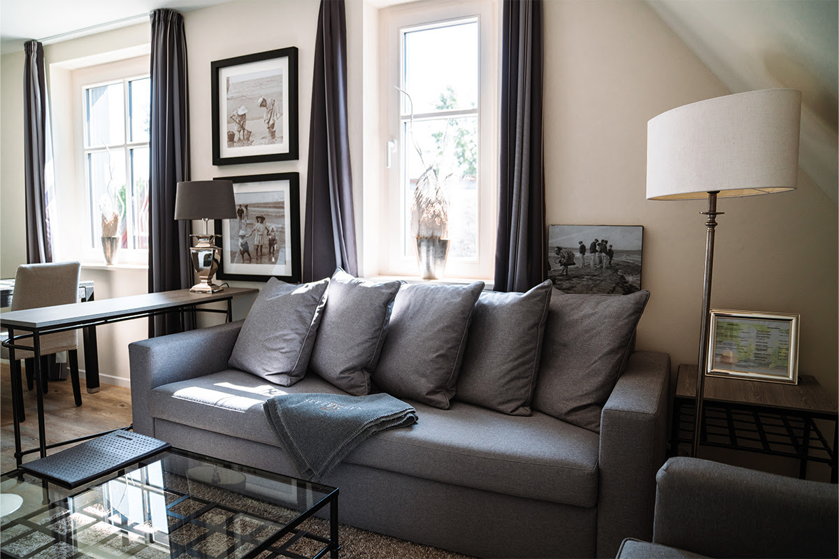Bright, modern living area of the Dünenpark vacation apartment in the Hotel Künstlerquartier Seezeichen with comfortable sofa.