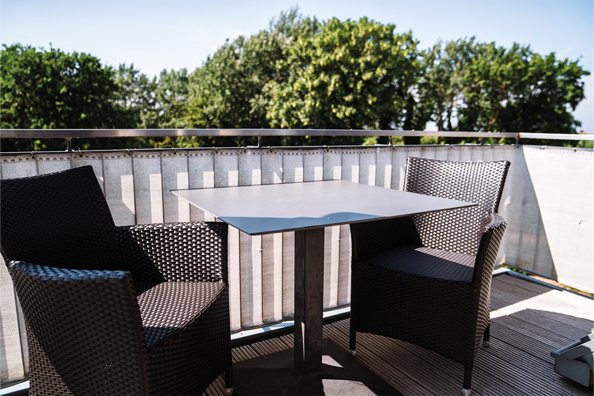 Sunny balcony of the Dünenpark vacation apartment in the Hotel Künstlerquartier Seezeichen with comfortable seating and lake view.