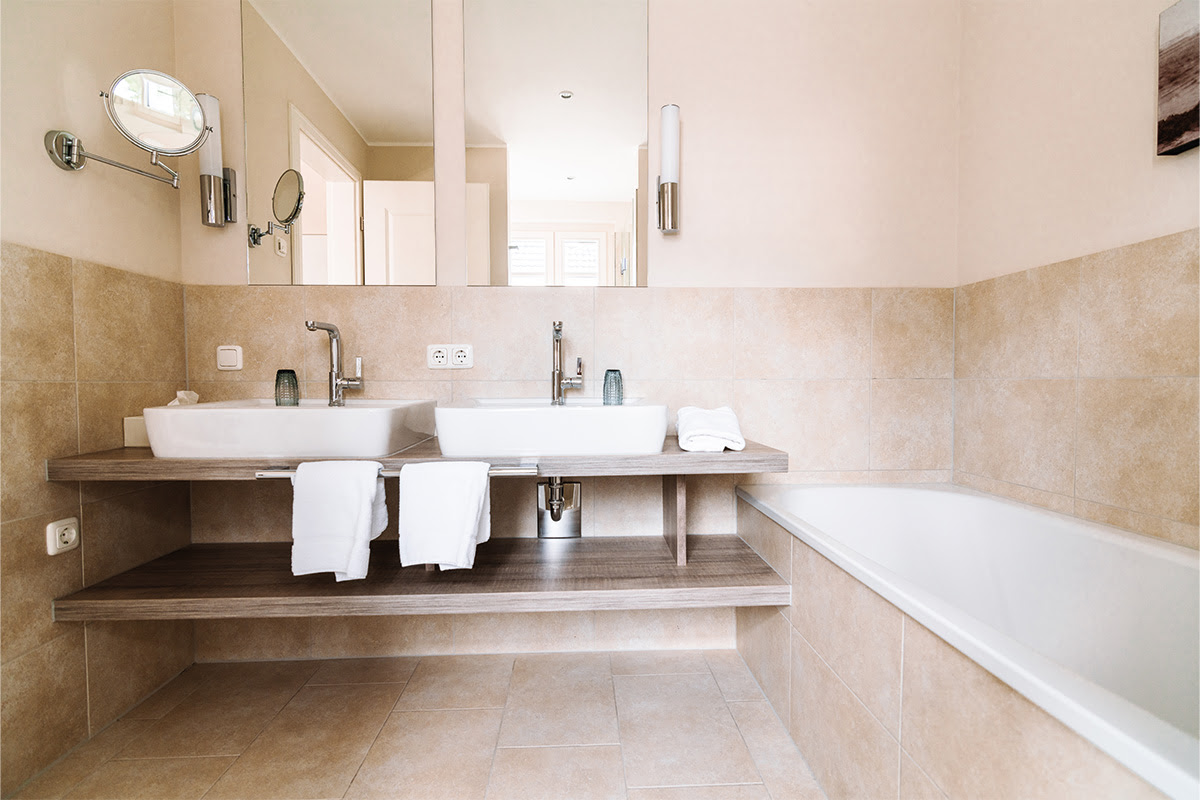 Modernes Badezimmer in der Ferienwohnung Seeigel im Künstlerquartier Seezeichen mit Doppelwaschbecken und Badewanne.