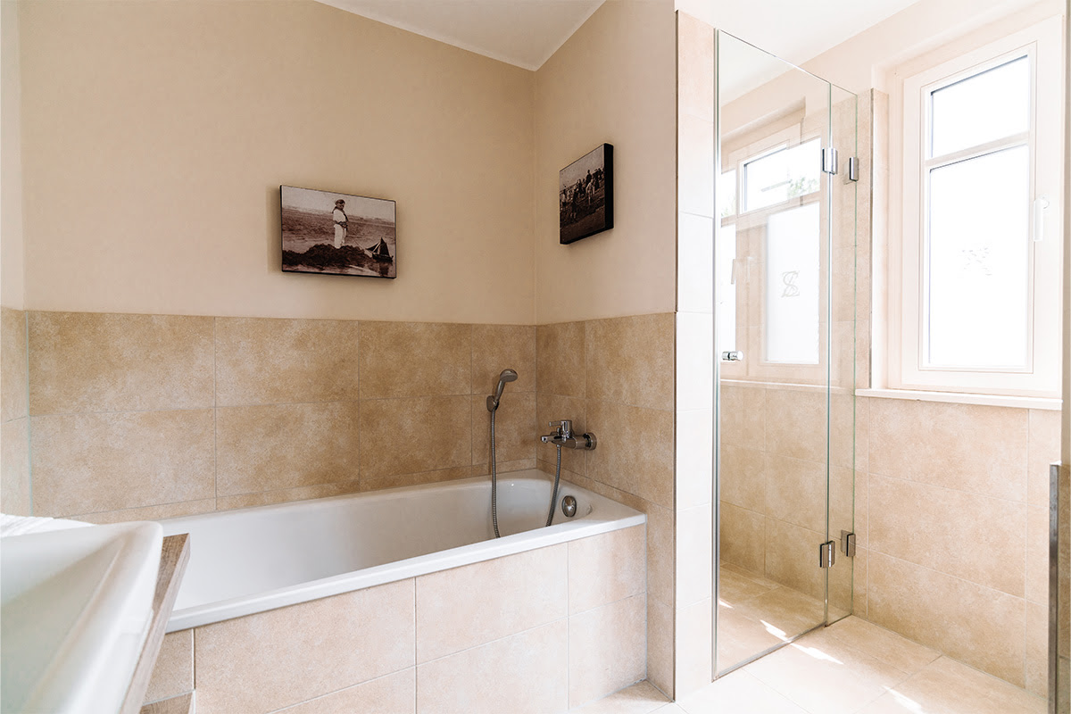 Helles Badezimmer der Ferienwohnung Seeigel mit Badewanne, Dusche und Tageslicht im Hotel Künstlerquartier Seezeichen.