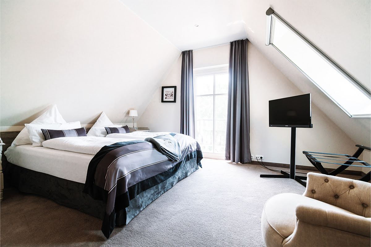 Helles Schlafzimmer mit Kingsize-Bett für eine ruhige Auszeit in der Ferienwohnung Seepferd im Hotel Künstlerquartier Seezeichen.