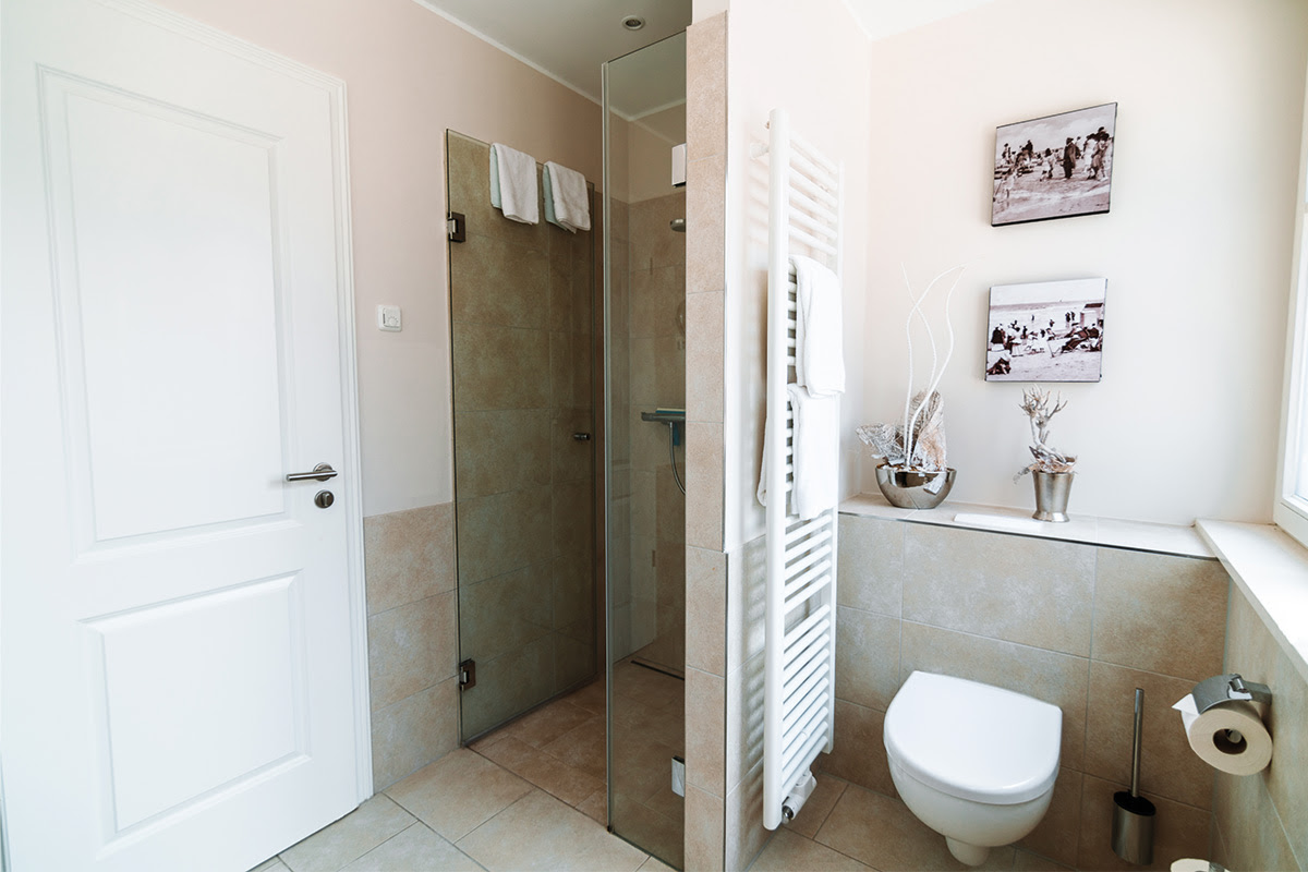 Bright bathroom with stylish interior and glass shower in the Stranddistel vacation apartment in the Hotel Künstlerquartier Seezeichen.