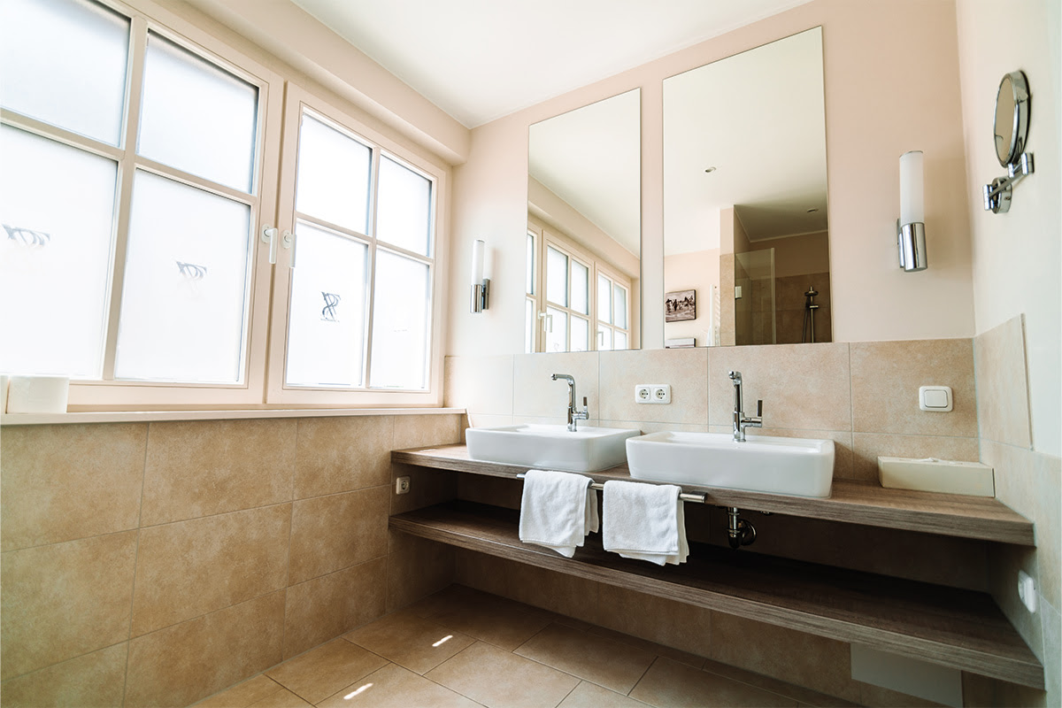 Double washbasin in the bathroom of the Stranddistil vacation apartment with a mirror and towels in the Ahrenshoop dune park.