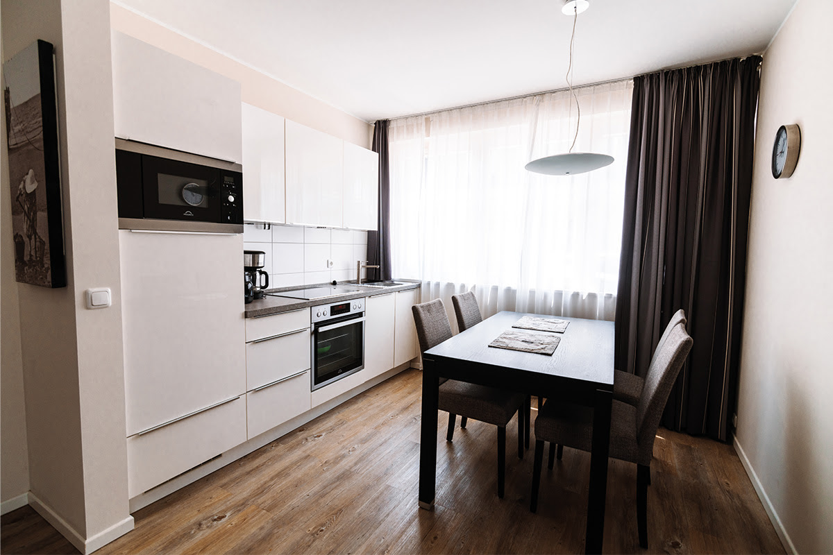 Open kitchen with dining table in the Stranddistel vacation apartment in the Dünenpark in Ahrenshoop with high-quality appliances.