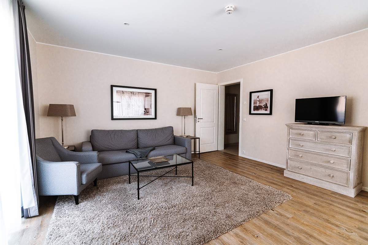 Wohnbereich der Ferienwohnung Strandmuschel mit bequemen Sitzmöglichkeiten und TV im Hotel Künstlerquartier Seezeichen.