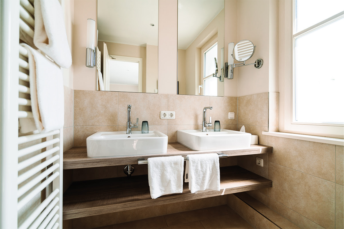 Bathroom with double washbasin and towels in the Strandperle vacation apartment at Hotel Künstlerquartier Seezeichen.