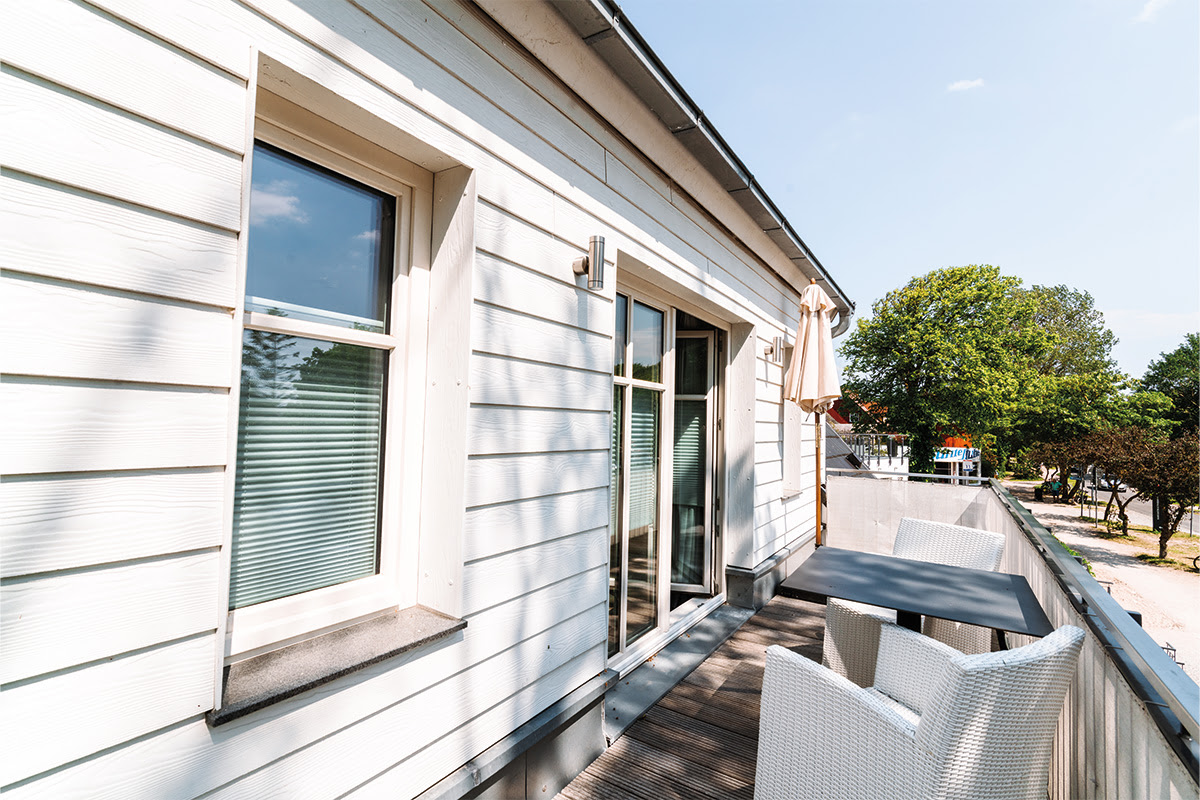 Exterior view of the balcony of the Strandperle vacation apartment in the Ahrenshoop dune park with comfortable seating.