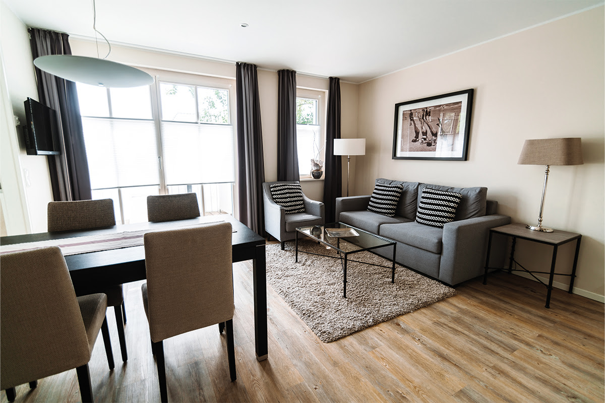 Comfortable living and dining area in the Strandperle vacation apartment in the Ahrenshoop dune park with modern furnishings.