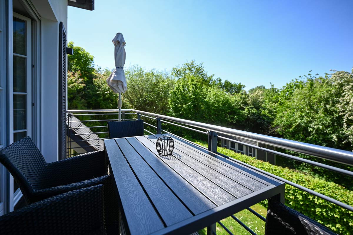 Balkon der Ferienwohnung Seeadler im Hotel Künstlerquartier Seezeichen mit modernen Möbeln und Blick ins Grüne.