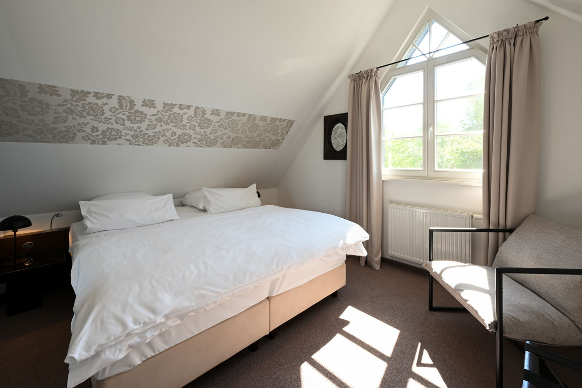Lichtdurchflutetes Schlafzimmer mit großem Doppelbett in der Ferienwohnung Seeadler des Hotels Künstlerquartier Seezeichen.