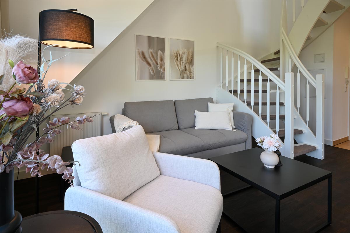 Stilvoller Wohnbereich mit Sofa und dekorativen Akzenten in der Ferienwohnung Seeadler im Hotel Künstlerquarter Seezeichen.