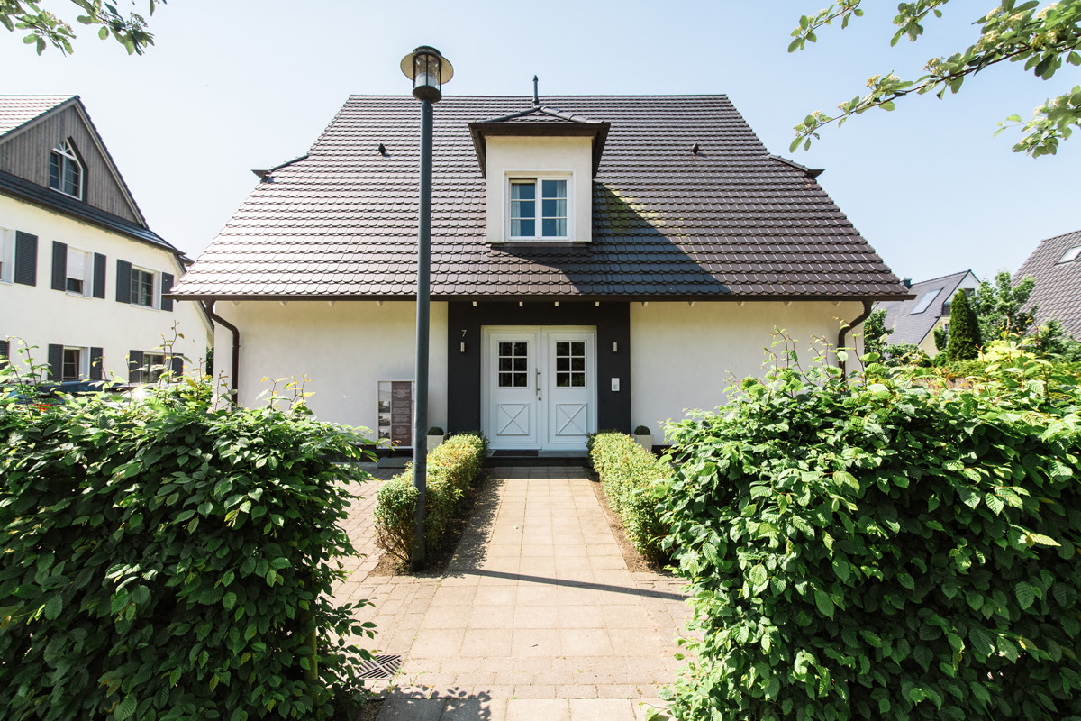 Exterior view of a vacation home of the Hotel Künstlerquartier Seezeichen with garden and paved path.