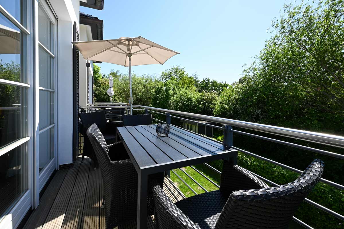 Private balcony of the Seestern vacation apartment with parasol and quiet garden view, part of the Künstlerquartier Seezeichen.