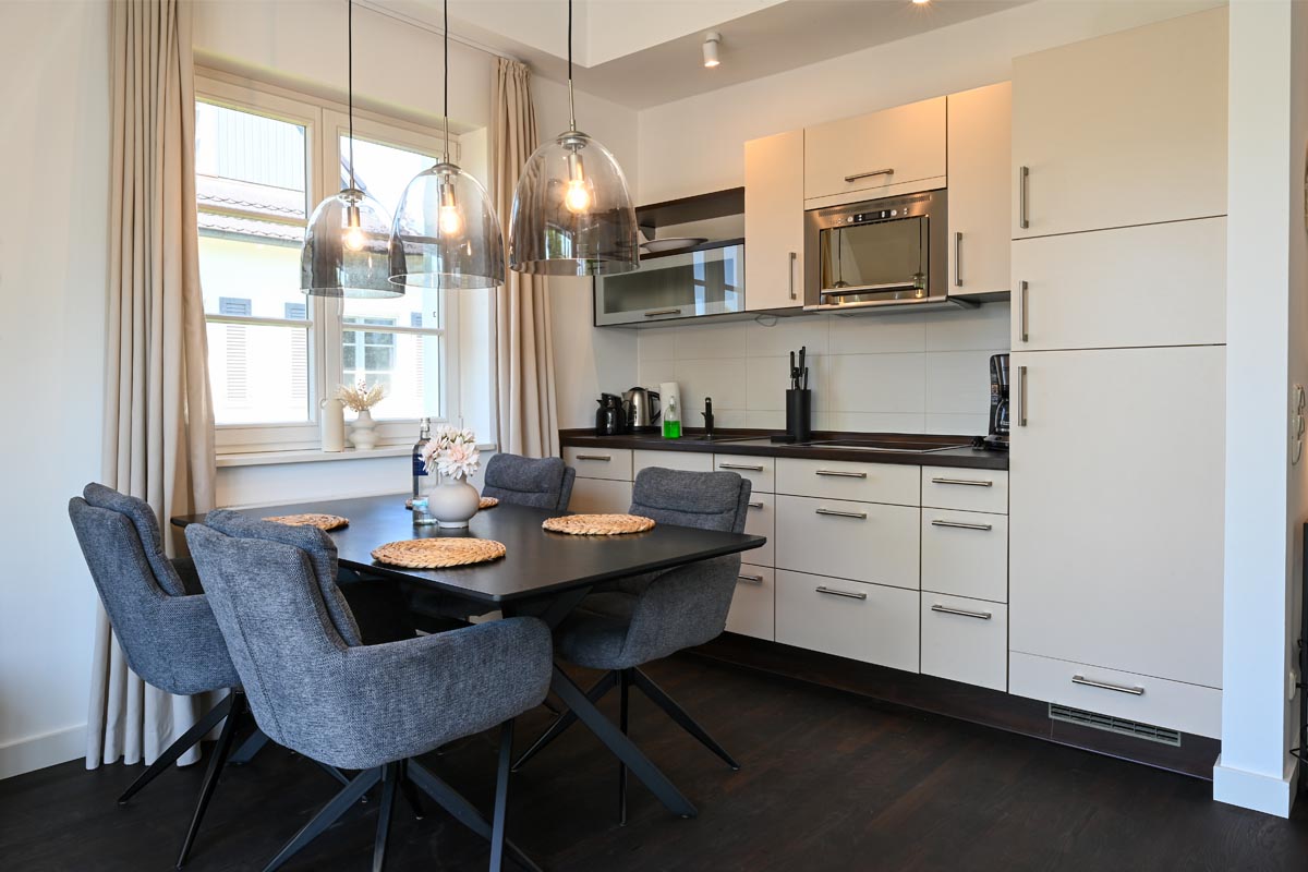 Open kitchen with modern equipment and dining area in the Seestern vacation apartment in the Hotel Künstlerquartier Seezeichen.