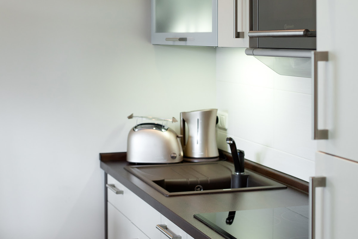 Compact, fully-equipped, open kitchenette in the Strandmöwe vacation apartment, part of the Hotel Künstlerquartier Seezeichen.