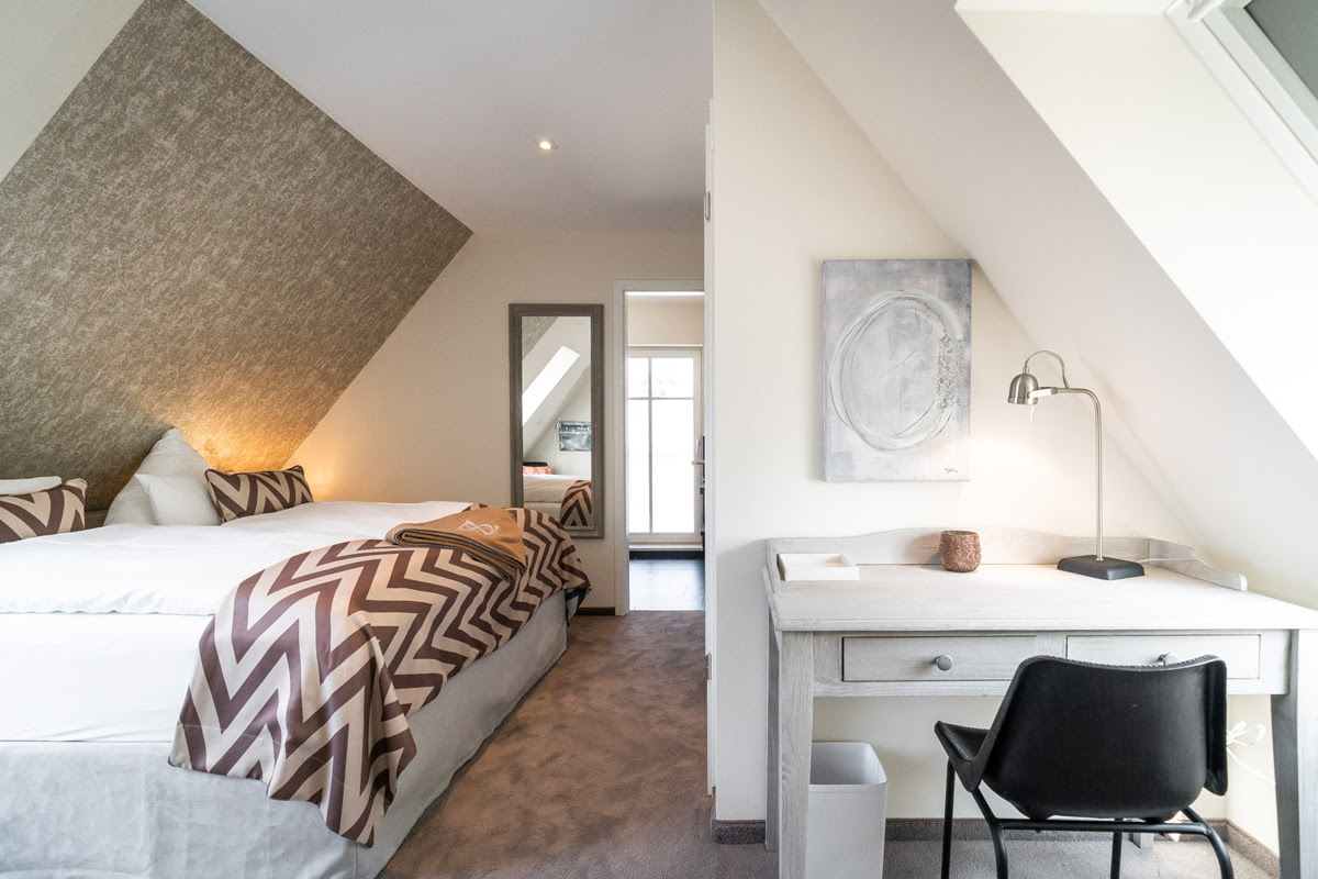 Dachgeschoss-Schlafzimmer mit gemütlichem Bett in der Ferienwohnung Strandjuwel im Hotel Künstlerquartier Seezeichen.