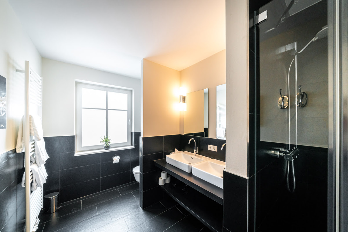 Bathroom of the Strandliebe vacation apartment in the Hotel Künstlerquartier Seezeichen with double washbasin and rain shower.