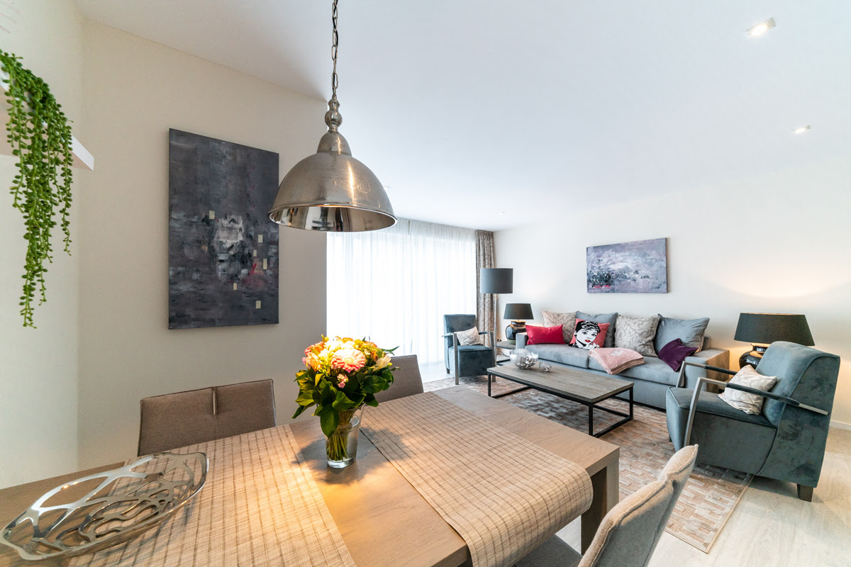 Dining area with dining table, upholstered chairs and view into the living room of the Strandliebe vacation apartment in the Künstlerquartier Seezeichen.