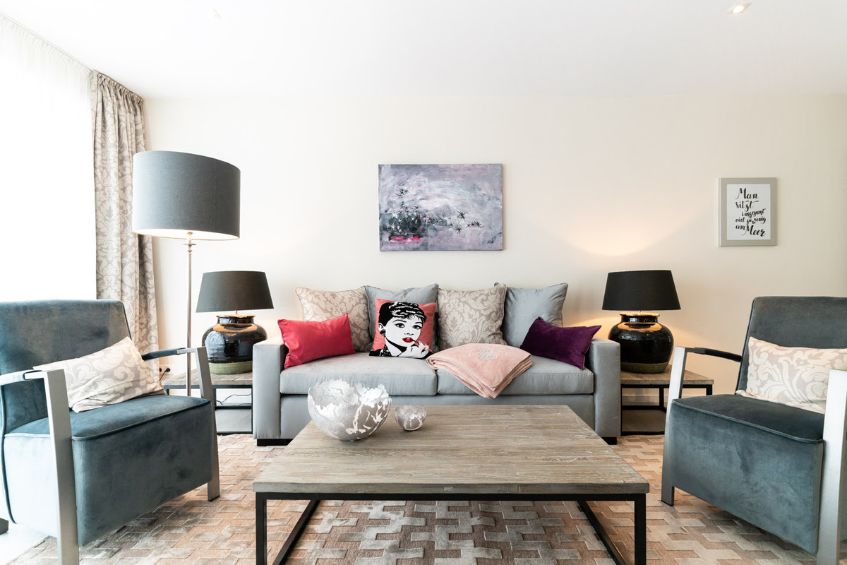 Living area with sofa, two armchairs and decorative elements in the Strandliebe vacation apartment in the Hotel Künstlerquartier Seezeichen.