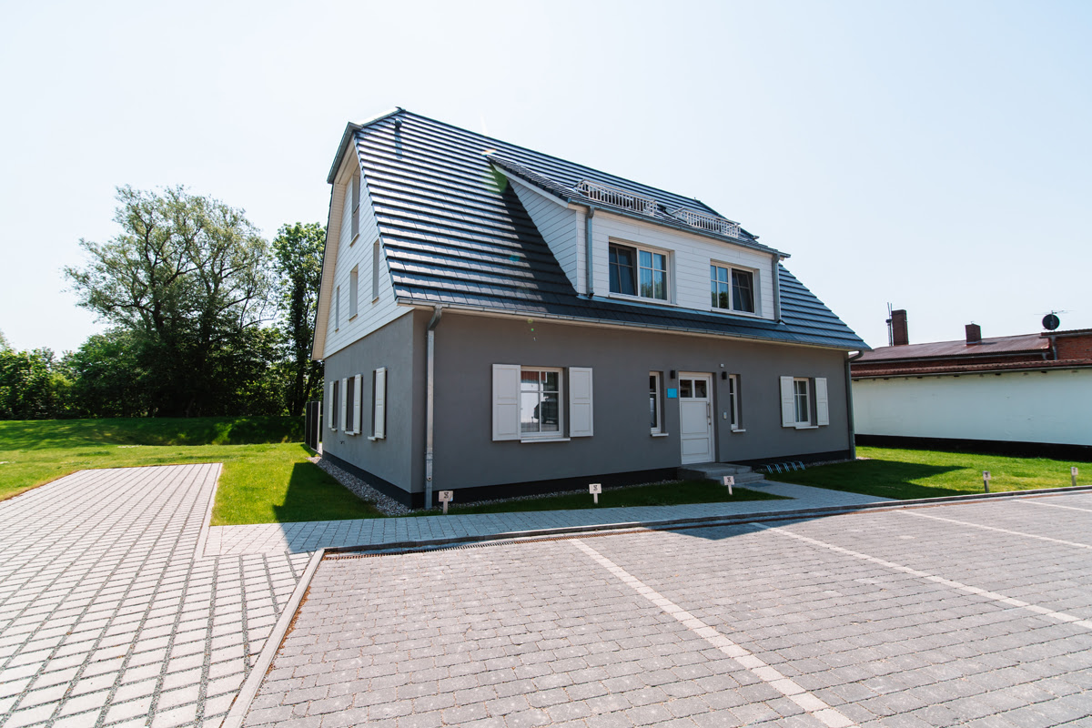 Exterior view of the modern beach villa with spacious parking lot and garden, part of the Hotel Künstlerquartier Seezeichen.