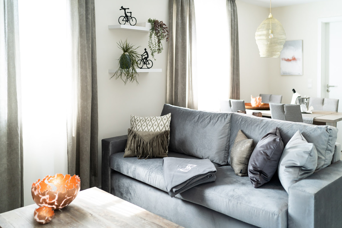 Bright living room with gray sofa and decorative cushions in the Strandoase vacation apartment in the Hotel Künstlerquartier Seezeichen.