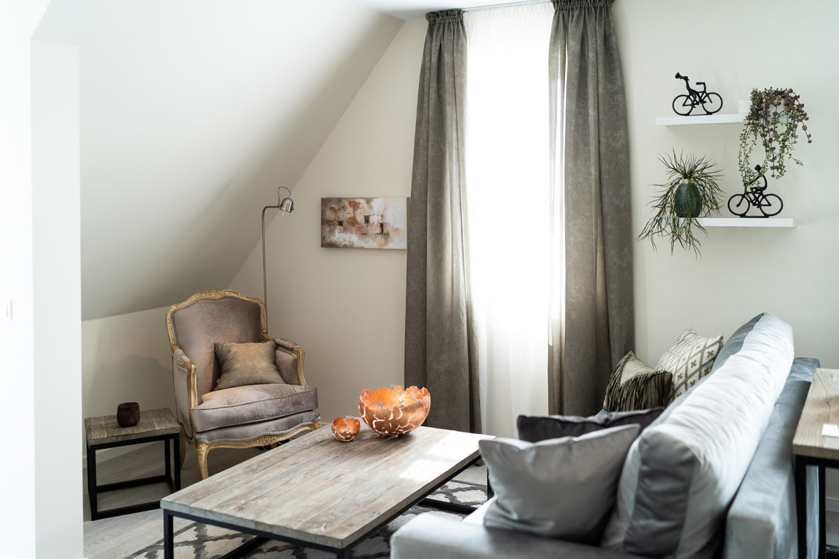 Living area with sofa, armchair and coffee table under a sloping roof of the Strandoase vacation apartment in the Strandvilla Ahrenshoop.