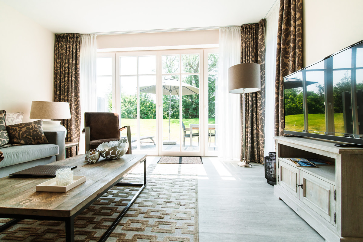 Living room with large window, sofa, armchair, coffee table and TV in the Strandvilla vacation apartment at the Künstlerquartier Seezeichen.