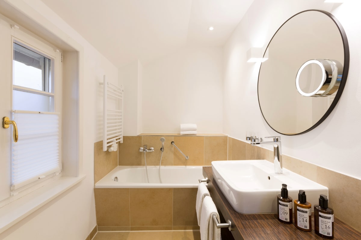 Helles, modernes Badezimmer der Elisabeth Galerie Suite im Hotel Künstlerquartier Seezeichen mit Tageslicht und Beauty-Produkten.