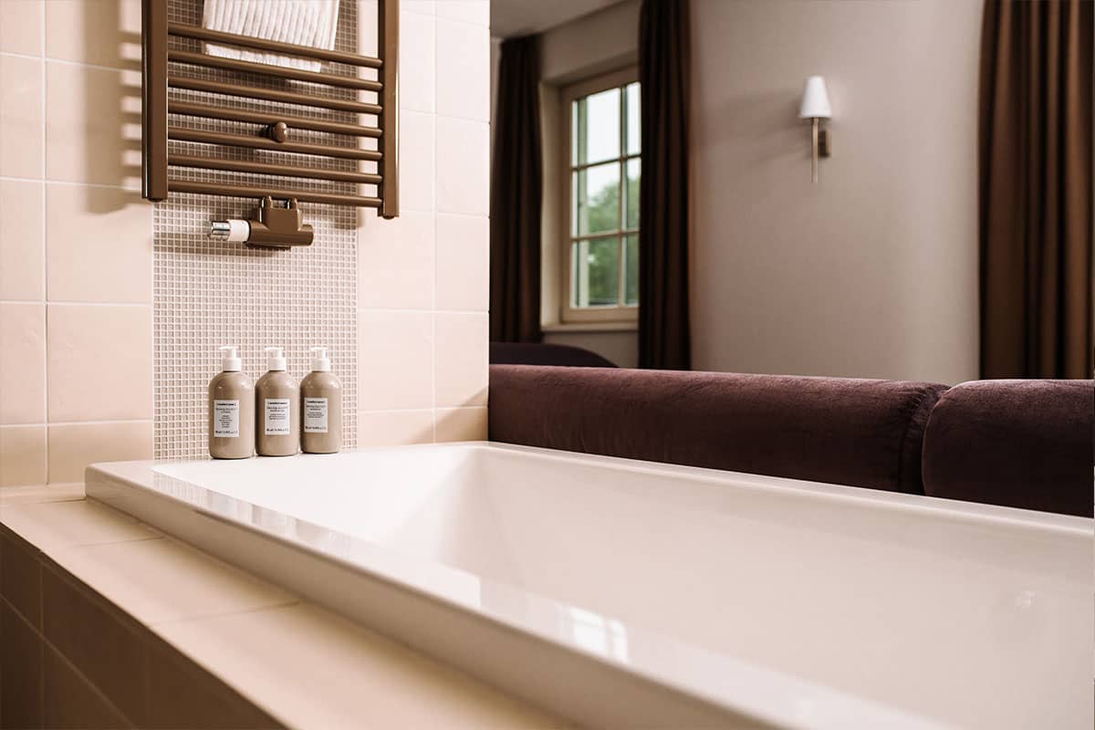 Free-standing bathtub in the open bathroom with a view of nature in the Deluxe Suite at Hotel Künstlerquartier Seezeichen.