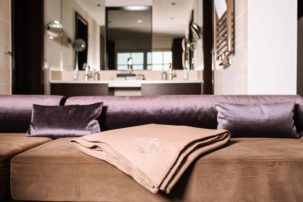 Luxurious bathroom with pillow and towel on a velvety cushion in the Deluxe Suite at Hotel Künstlerquartier Seezeichen.