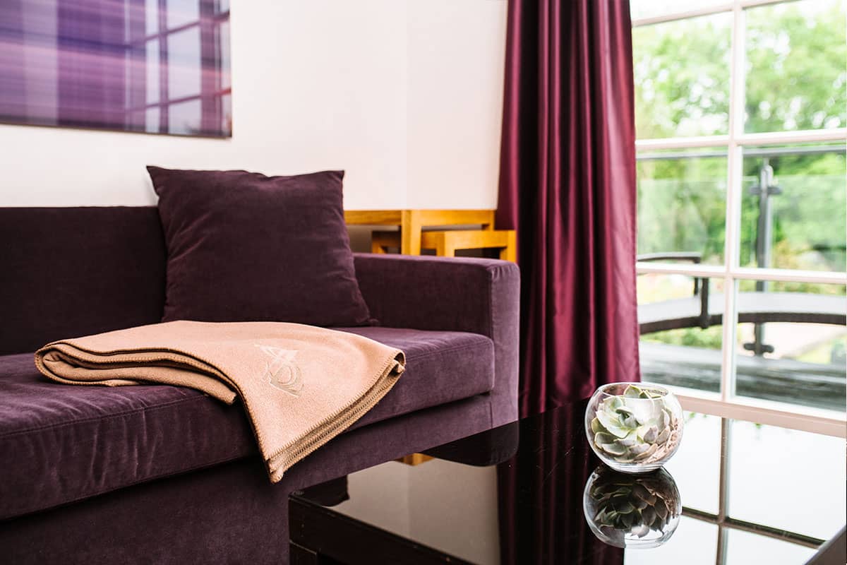Close-up of a cozy couch with soft cushions and a blanket in the Deluxe Suite of the Hotel Künstlerquartier Seezeichen.