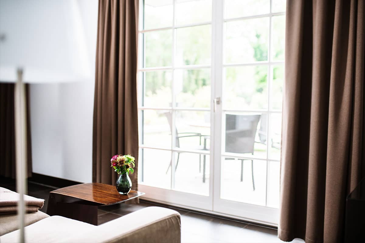 Einladender Blick ins Freie durch die Fensterfront der Junior Suite im Hotel Künstlerquartier Seezeichen mit gemütlichem Ambiente.