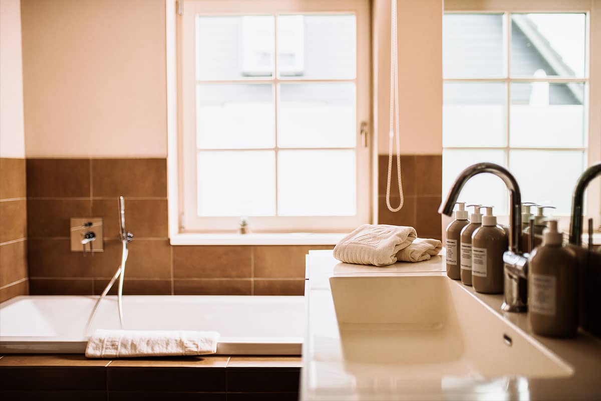 Stilvolles Bad mit Badewanne, Waschbecken und Kosmetikartikeln in der Junior Suite des Hotel Künstlerquartier Seezeichen.
