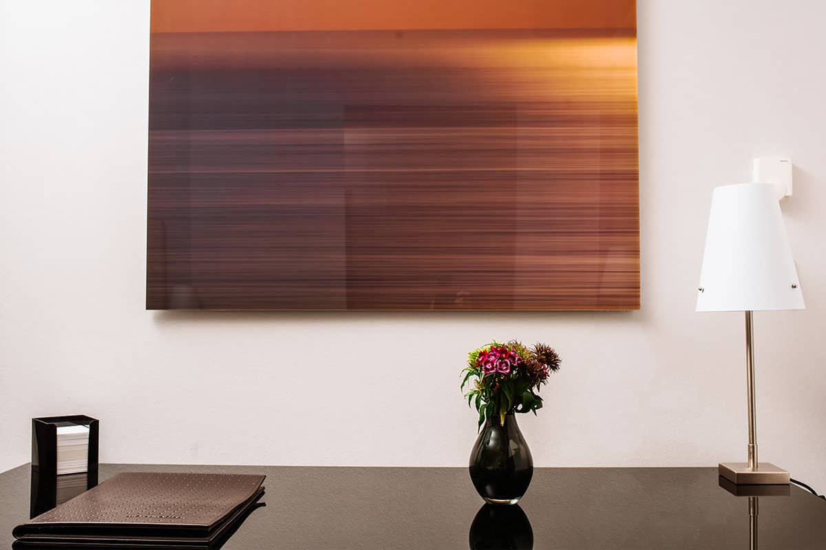 Schreibtisch mit moderner Lampe, Blumen und Notizbuch in der Junior Suite des Hotel Künstlerquartier Seezeichen.