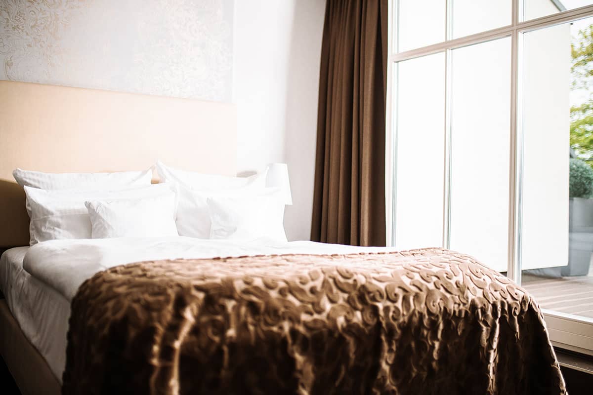 Ein großzügiges Doppelbett mit eleganter Bettwäsche im Comfort-Doppelzimmer im Hotel Künstlerquartier Seezeichen.