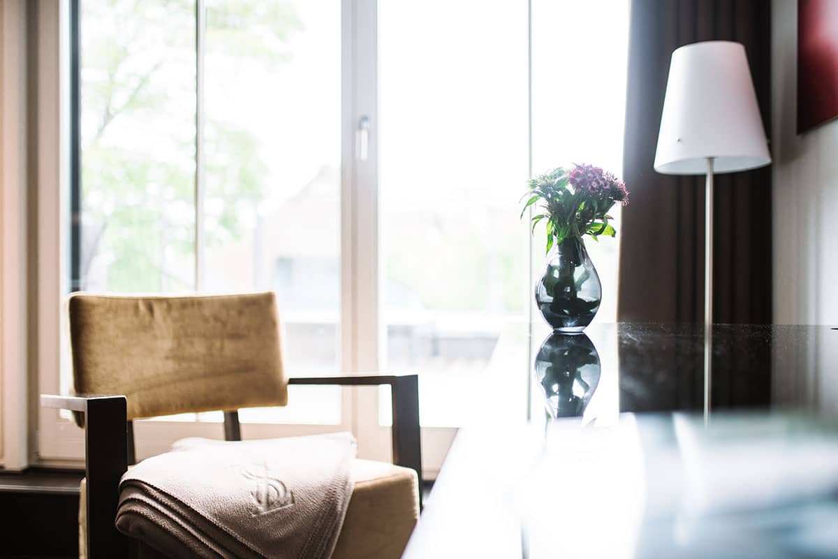 Ein gemütlicher Stuhl und Blumenarrangement im Comfort-Doppelzimmer des Hotel Künstlerquartier Seezeichen.