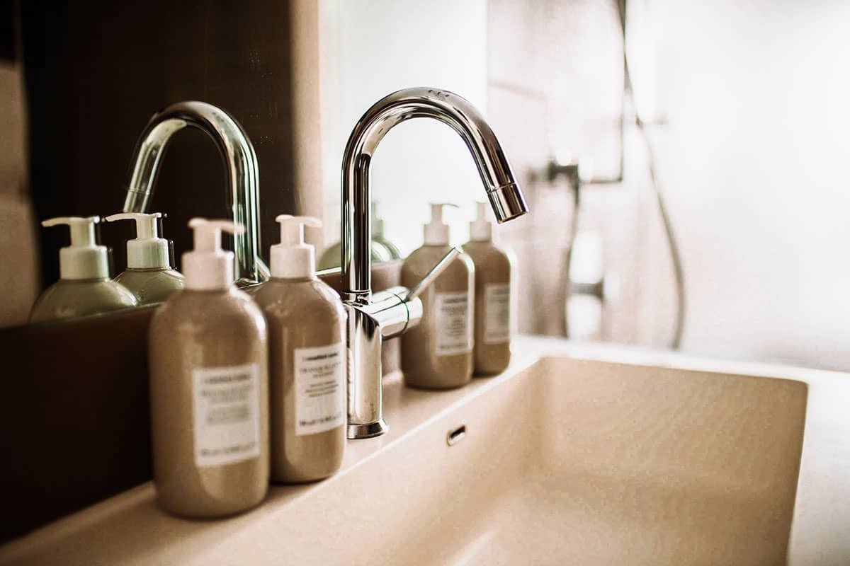 Nahaufnahme eines Wasserhahns mit eleganten Pflegeprodukten im Comfort-Doppelzimmer des Künstlerquartier Seezeichen.