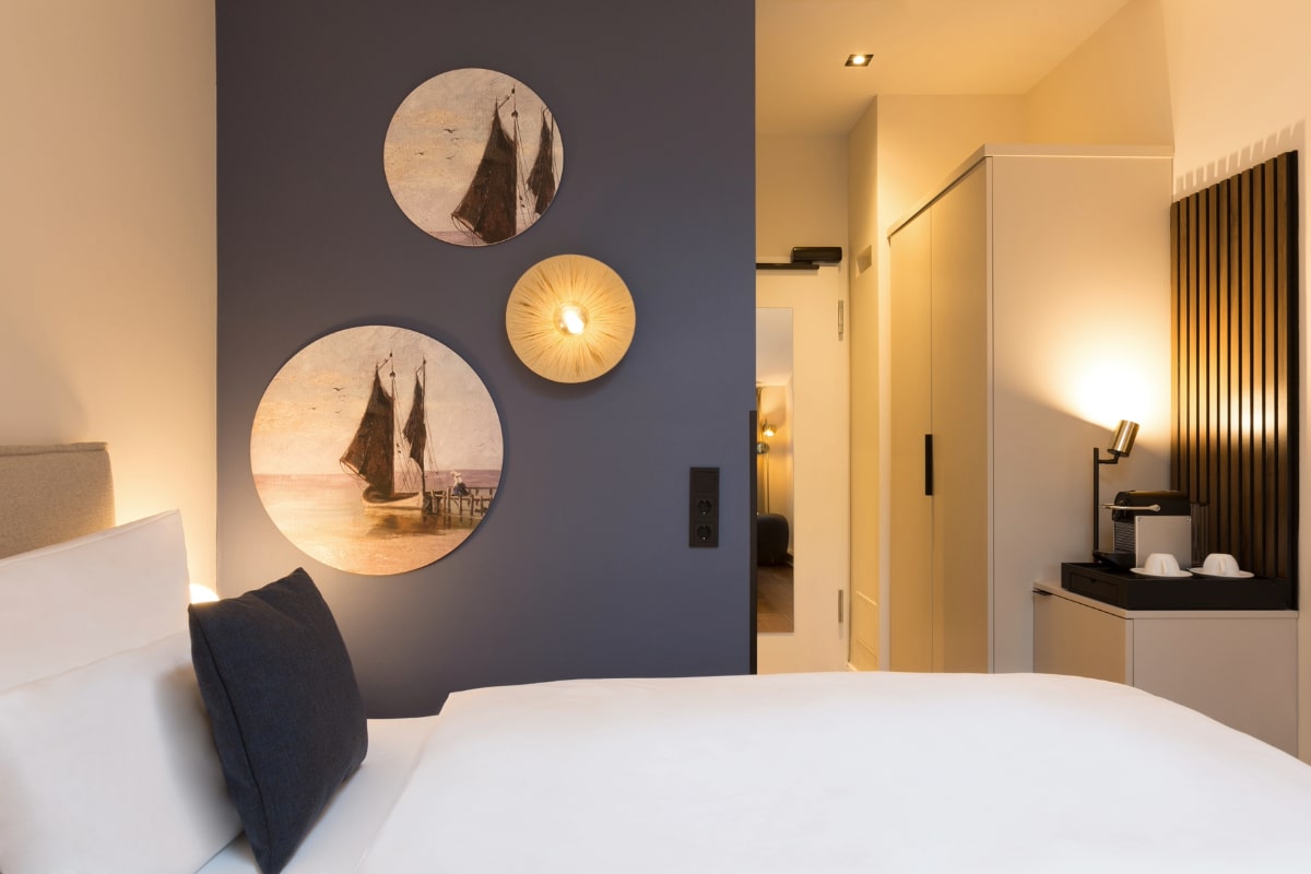 Einzelzimmer mit maritimer Wanddekoration, stilvoller Einrichtung und komfortablem Bett im Elisabeth von Eicken Hotel.